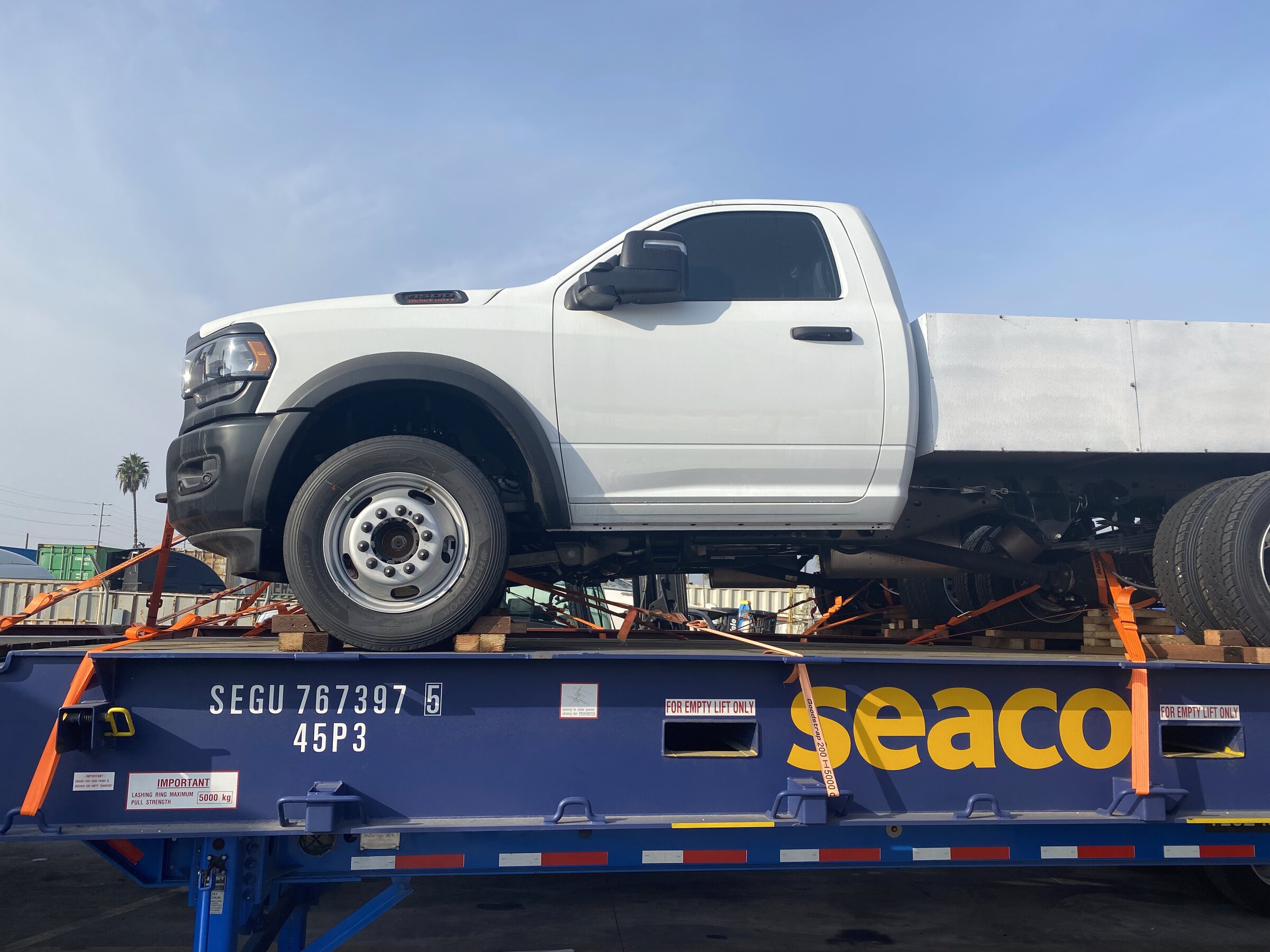 Workers chaining and securing wrapped cargo on a flatbed